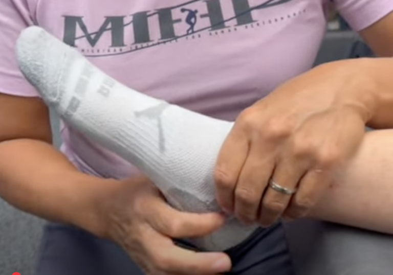 Person massaging foot in white sock.